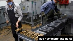 کارکنان شرکتی در شهر کراسنویارسک سیبری روسیه در حال خارج کردن شمش طلای ریختهگری شده از قالب