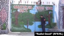 Un gardian, privind printr-o gaură în poarta Penitenciarului din Dușanbe, capitala Tadjikistanului. În mod Ironic, pe poartă este desenat un peisaj, sugerând libertatea
