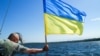 Матрос ВМС на тлі величезного прапора України на фрегаті «Гетьман Сагайдачний» під час навчань «Сі бриз-2018». Одеса, 16 липня 2018 року