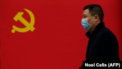 Чоловік у масці на тлі прапора Китаю, Ухань, 31 березня 2020 року