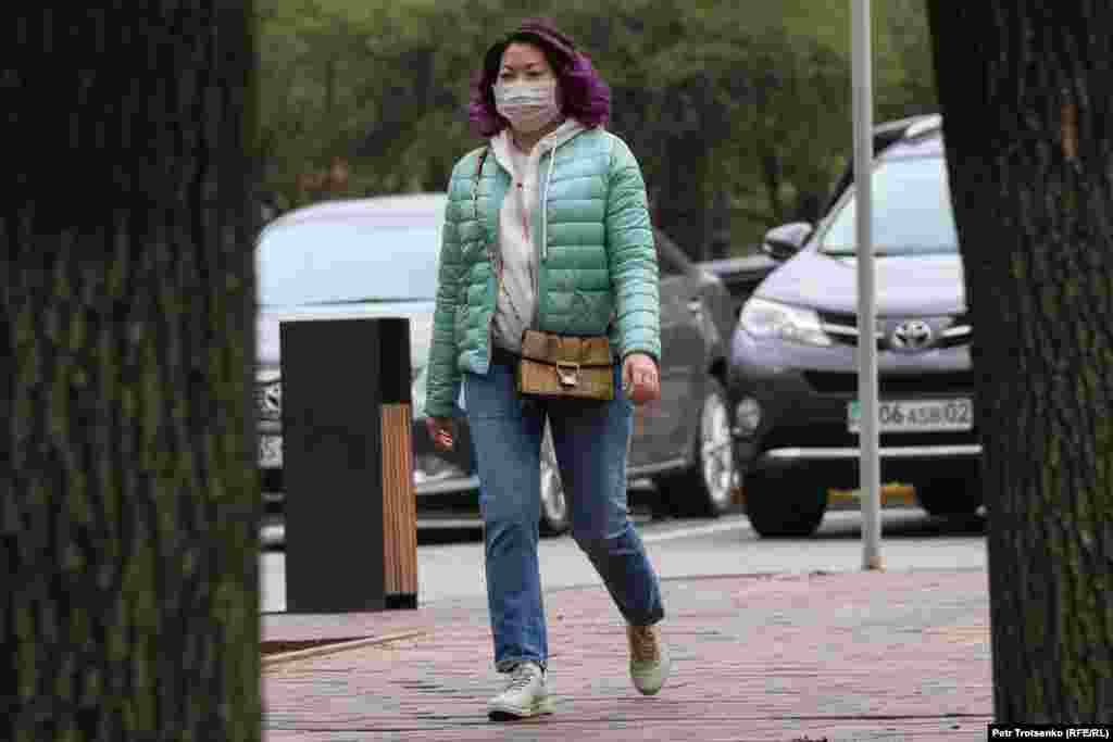 Женщина в маске идет по одной из центральных улиц Алматы.
