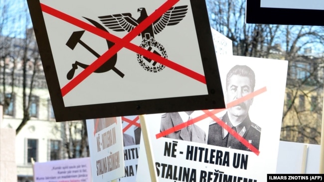 Плакати із засудженням нацизму і комунізму на акції у столиці Латвії. Рига, 16 березня 2013 року