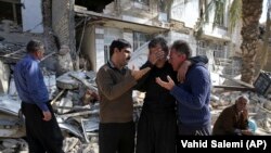 Earthquake survivors mourn in front of destroyed houses in Sarpol-e-Zahab in western Iran, Wednesday, Nov. 15, 2017