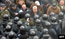 Un protestatar argumentează cu poliția astăzi, 23 dec., în fața parlamentului de la Kiev, in momentul în care deputații au votat renunțarea la statutul de neutralitate.