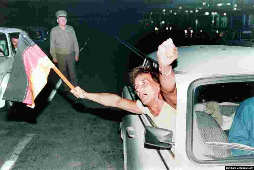 An East German waves a West German flag while crossing from Hungary into Austria early on September 11, 1989, the first day of eased travel restrictions to the West.&nbsp;