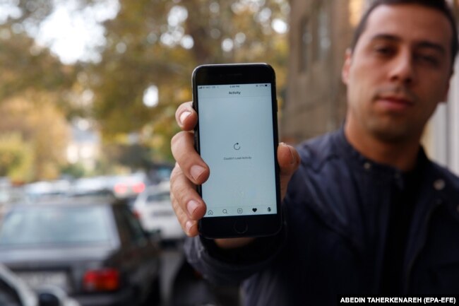 An Iranian man shows his phone while unable to load a social media page as internet service is reportedly disrupted, Tehran, Iran, 17 November 2019.