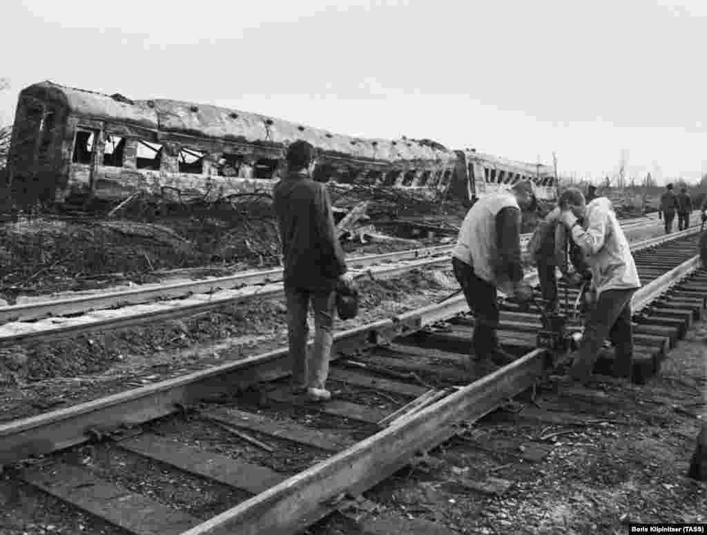 Emergency teams work to restore the railroad in the shadow of a wrecked train.