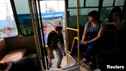 Russian police officers escort detained migrant workers to a police bus during a spot check at a market in the Siberian city of Krasnoyarsk on August 7.