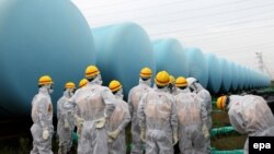 A file handout picture taken on 23 August and provided by the Japan Nuclear Regulation Authority shows members inspecting makeshift storage tanks at the Fukushima Daiichi nuclear power plant crippled by tsunami following the massive earthquake in March 2011.