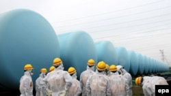Japan Nuclear Regulation Authority (NRA) members are seen here wearing protective suits and masks while they inspect makeshift storage tanks.