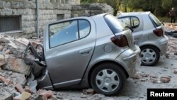 Destroyed cars stand next to a damaged building after an earthquake in Tirana on September 21.