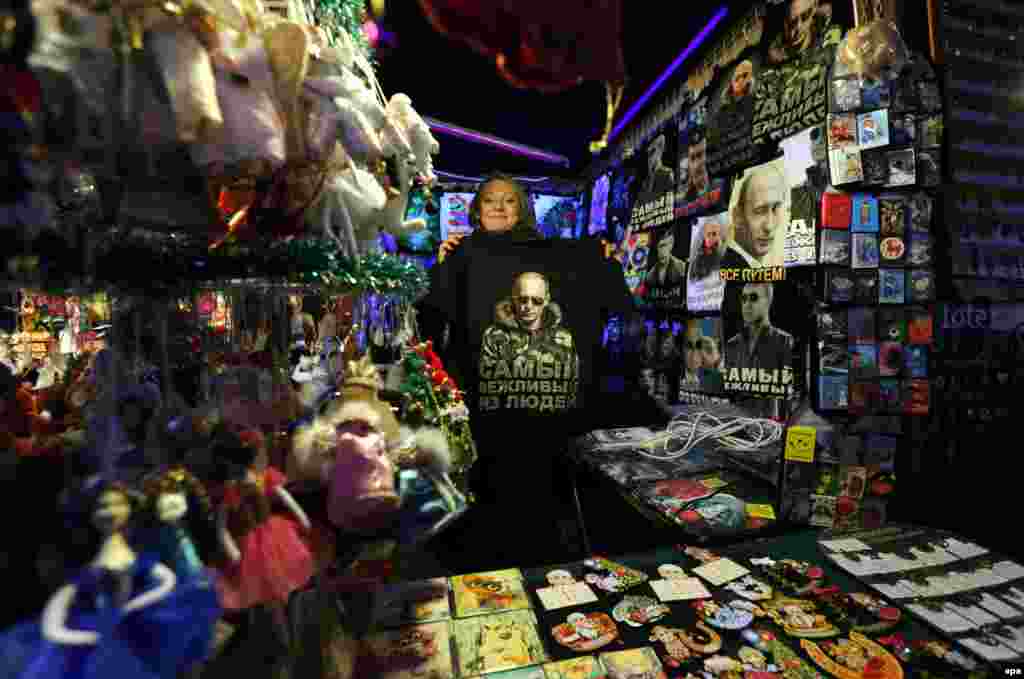 A street vendor shows a T-shirt with a portrait of Russian President Vladimir Putin at a Christmas market in St. Petersburg. (epa/Anatoly Maltsev)