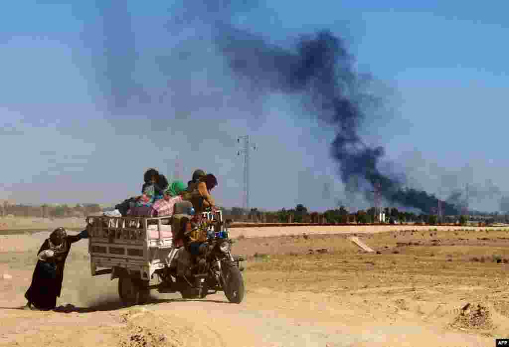 An Iraqi woman and some children flee the town of Hit in Anbar Province after government forces ordered an evacuation on April 4. (AFP/Moadh Al-Dulaimi)