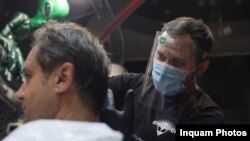 Angajati ai unei frizerii lucreaza in primele minute ale zilei de 15 mai, prima zi de stare de alerta cauzata de pandemia de Covid-19, in Bucuresti, vineri, 15 mai 2020