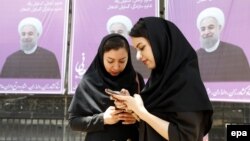 Iranian women stand in front of election posters for President Hassan Rohani in city of Karaj.