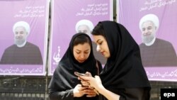 Iranian women stand in front of campaign posters for President Hassan Rohani in the city of Karaj.