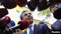 Georgia -- Leader of the opposition Georgian Dream coalition Bidzina Ivanishvili (C) addresses the media near his wife Eka Khvedelidze (R), who voted at a polling station during the parliamentary election, in Tbilisi.