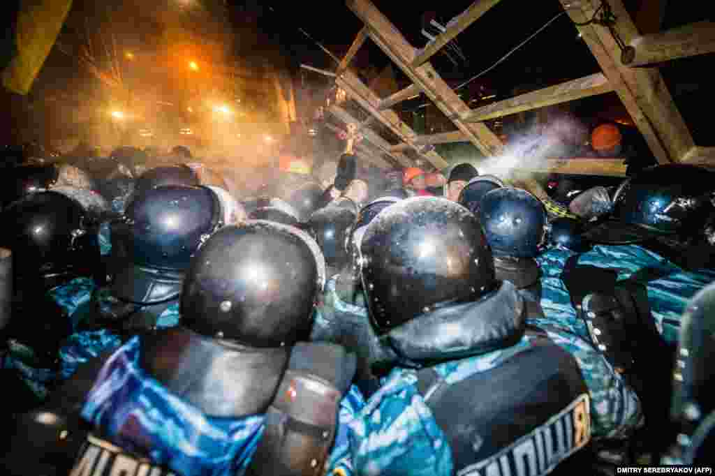 2013 йил 11 декабр: Украина милицияси Мустақиллик майдонида намойишчилар томонидан қурилган баррикадани бузиб ташлашга уринмоқда. &nbsp;
