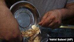 In this Wednesday, Aug. 12, 2018 photo, an Iranian goldsmith counts gold coins in the sprawling Grand Bazaar, that has seen customers eagerly buying gold as a hedge against the falling Iranian rial, in Tehran, Iran.