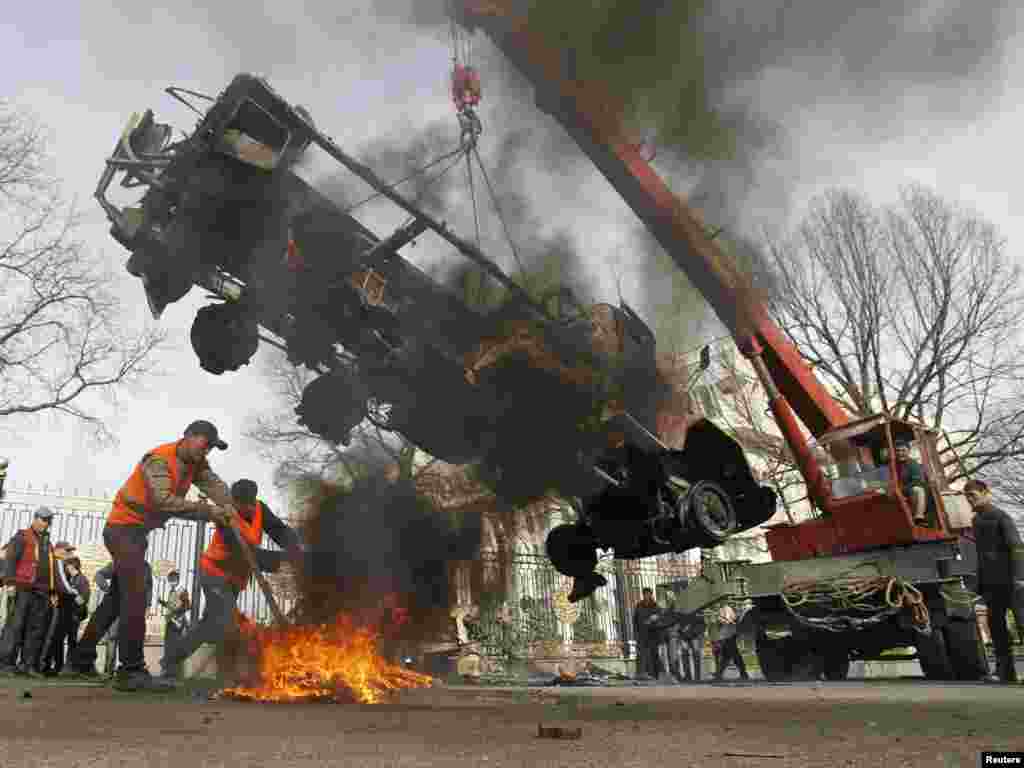 Рабочие убирают сгоревший грузовик с одной из центральных улиц Бишкека. 9 апреля 2010 года.