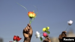 Opposition supporters wave roses during an antigovernment protest in Sanaa on January 26.