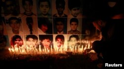 During a candlelight vigil in Lahore on December 19, a man places a rose after lighting candles in front of portraits of the victims of the Taliban attack on a school in Peshawar.