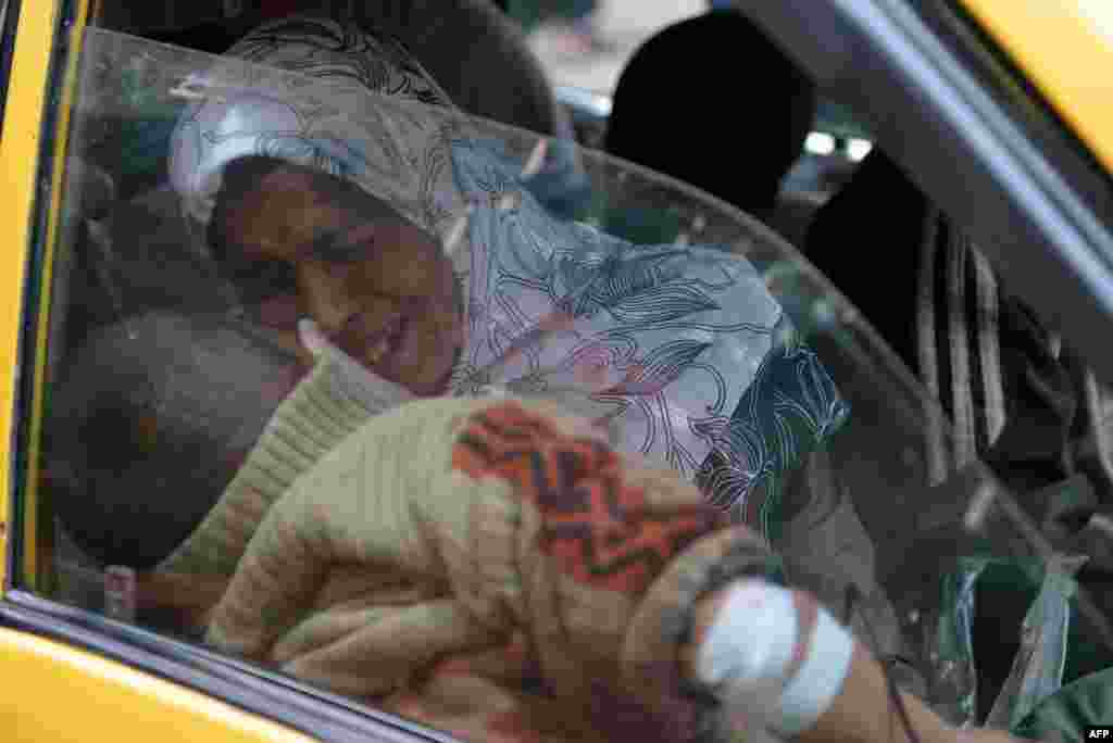 A Syrian woman holds her injured son in a taxi as they arrive at a hospital in the northern city of Aleppo following shelling by government forces. (AFP/Aamir Qureshi)