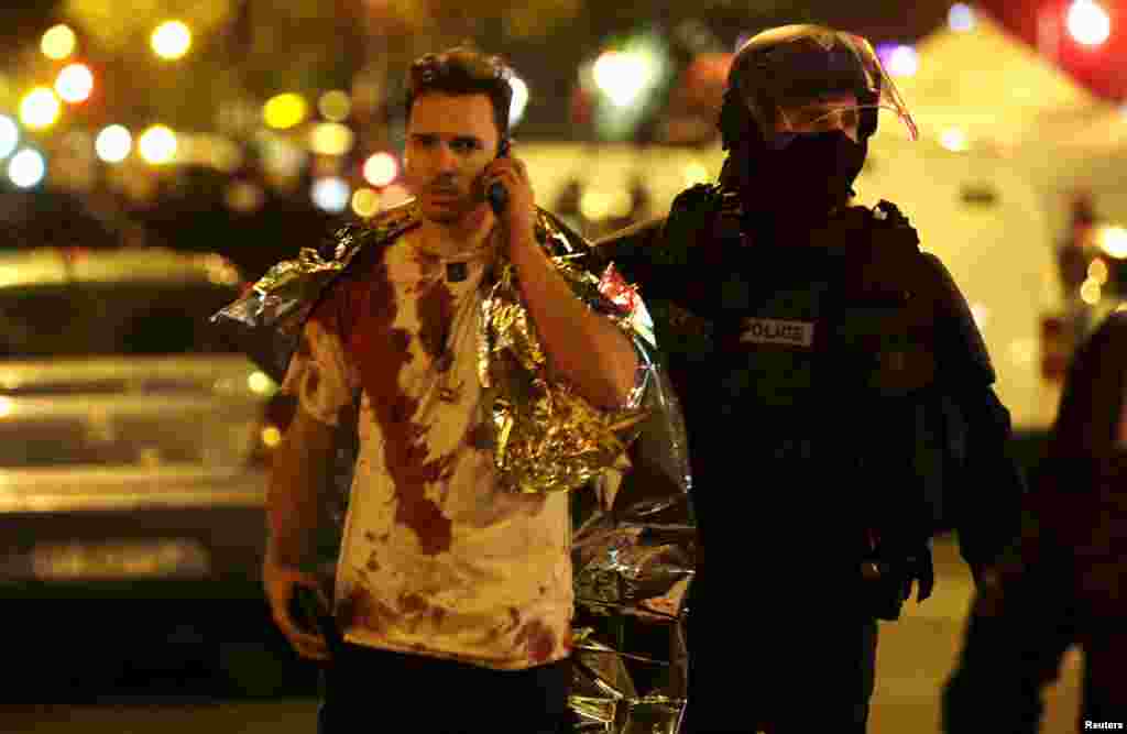 A French policeman assists a blood-soaked victim near the Bataclan concert hall.