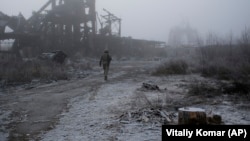 A Ukrainian soldier walks through the fog, past a destroyed coal mine, as he approaches his frontline position in the town of Avdiyivka in the Donetsk region on November 19.