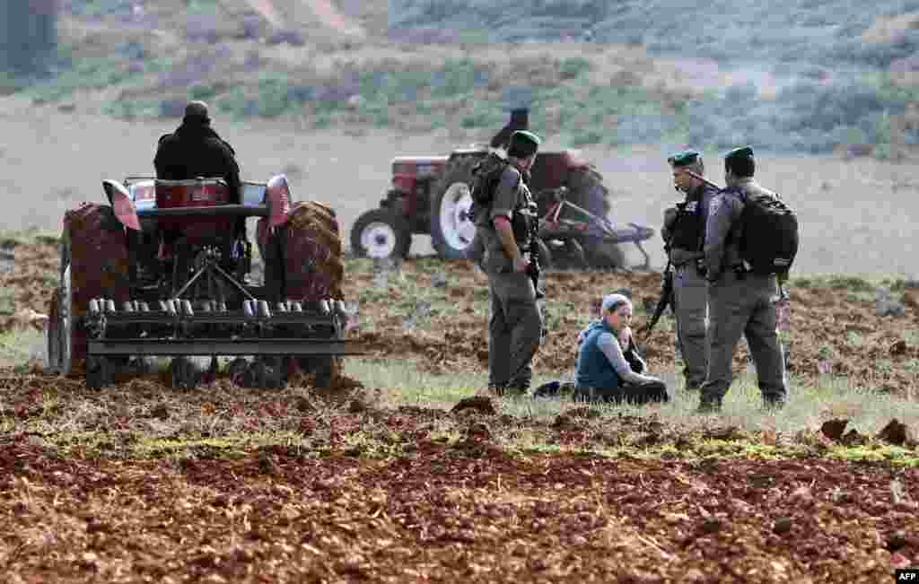 Cisiordania - Soldaţi israelieni discută cu coloniştii evrei din Esh Kodesh, în încercarea de a preveni angajarea palestinienilor la munci agricole, mai la nord de localitatea Jalod. 2 ianuarie 2013 (AFP/JAAFAR ASHTIYEH)