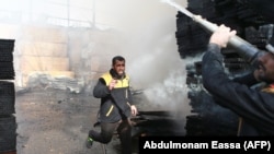 Anëtarë të Mbrojtjes Civile Siriane, të njohur edhe si “Helmetat e Bardha”, shuajnë zjarrin pas sulmeve ajrore në Gutan Lindore.