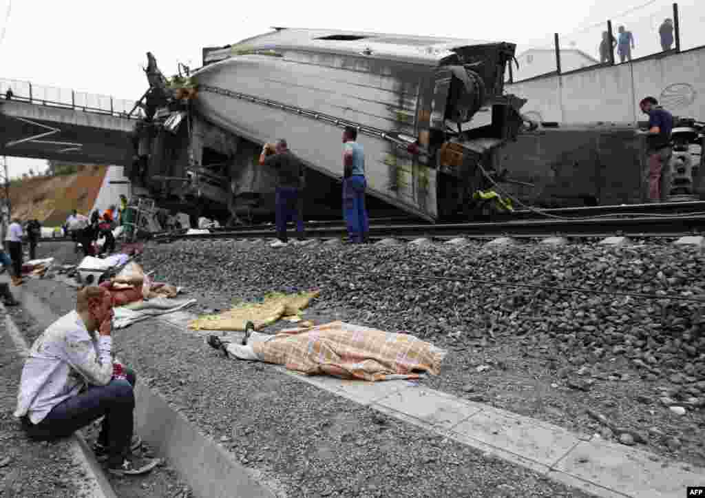 An injured man sits next to the body of one of the some 80 victims killed when a train derailed at high speed on July 24 near the Spanishi city of Santiago de Compostela. (AFP)