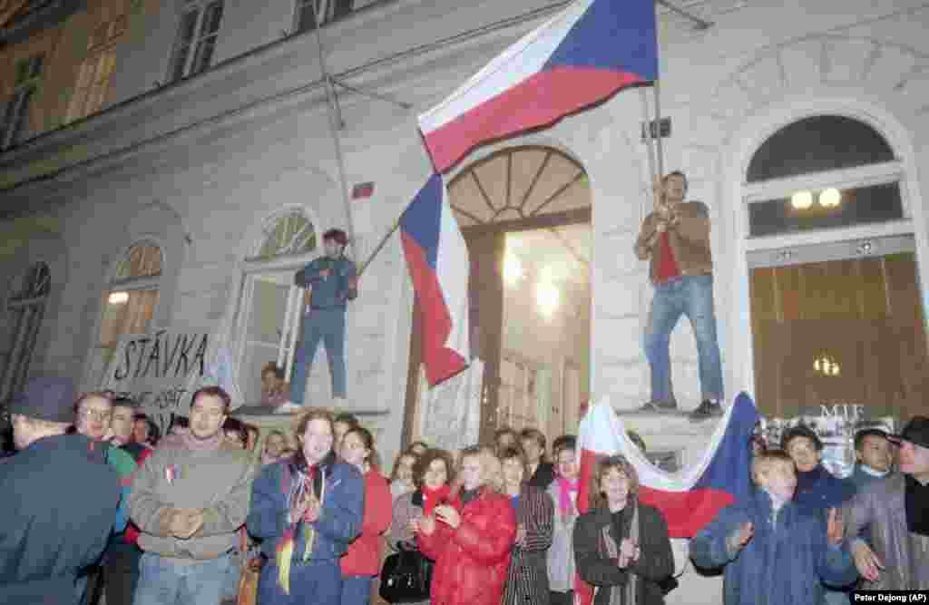 Протестиращи развяват знамето на Чехословакия пред Националната филмова академия в подкрепа на обявилите стачка студенти и актьори.&nbsp;