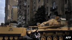 An Egyptian woman stands in front of tanks blocking the street outside the state television building during a demonstration by Coptic Christians in Cairo on March 10.