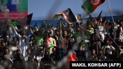 AFGHANISTAN -- In this photograph taken on September 18, 2017, Afghan cricket fans cheer and wave the national flag during a match between Kabul Eagles and Band-e-Amir Dragons during the Shpageeza Cricket League T20 tournament at the Kabul International C
