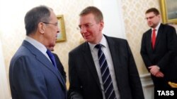 Russia's foreign minister, Sergei Lavrov (L), and Latvian Foreign Minister Edgars Rinkevics shake hands at a meeting.