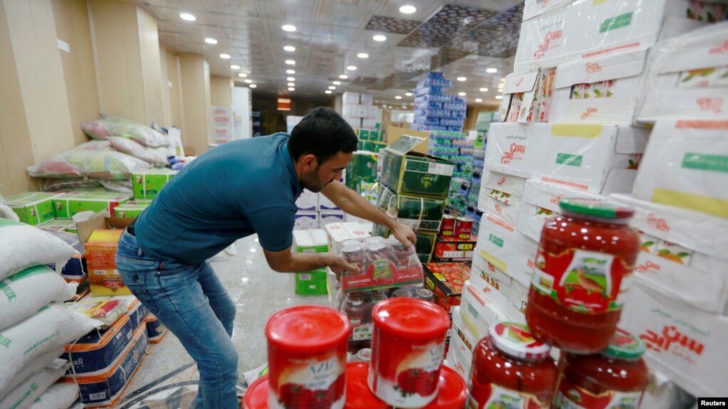 A shop worker arranges the cans of Iranian tomato paste at a super market in the city of Najaf, Iraq October 7, 2018. Picture taken October 7, 2018. REUTERS/Alaa Al-Marjani