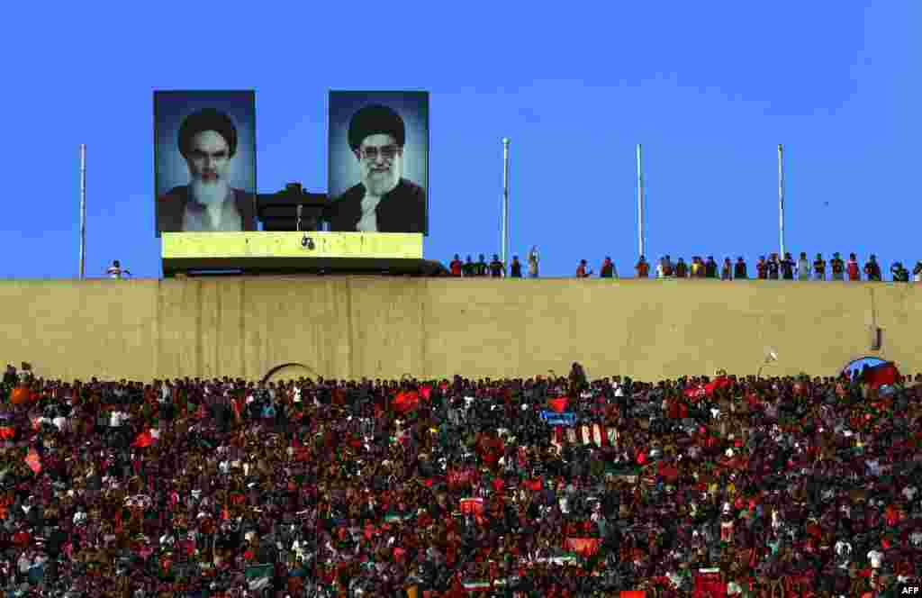 Fans of Iran's Persepolis football club cheer on their team during their AFC Champions League match against Saudi Arabia's Al-Hilal club at the Azadi stadium in Tehran. The posters show portraits of Iran's Supreme Leader Ayatollah Ali Khamenei (right) and the founder of the Islamic republic, Ayatollah Ruhollah Khomeini. (AFP/Atta Kenare)