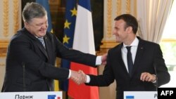 French President Emmanuel Macron (right) shakes hands with his Ukrainian counterpart, Petro Poroshenko, during a joint press conference after a meeting at the Elysee Palace in Paris on June 26.