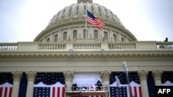 Workers adjust the U.S. flag on the Capitol as preparations continue for the second inauguration of President Barack Obama.