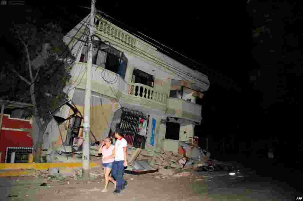 Residents walk on a street amid destroyed buildings following an earthquake on April 16 in Guayaquil, Ecuador. At least 28 people were killed by a strong 7.8-magnitude earthquake that struck the country&#39;s northwest. (AFP/Ariel Ochoa)