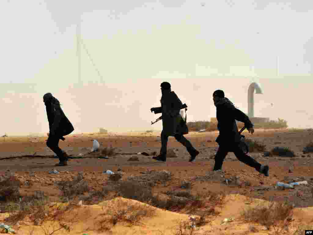 Libyan rebel fighters run to give assistance to their comrades some 10 kilometers east of the key oil port of Ras Lanuf. Photo by Roberto Schmidt for AFP 