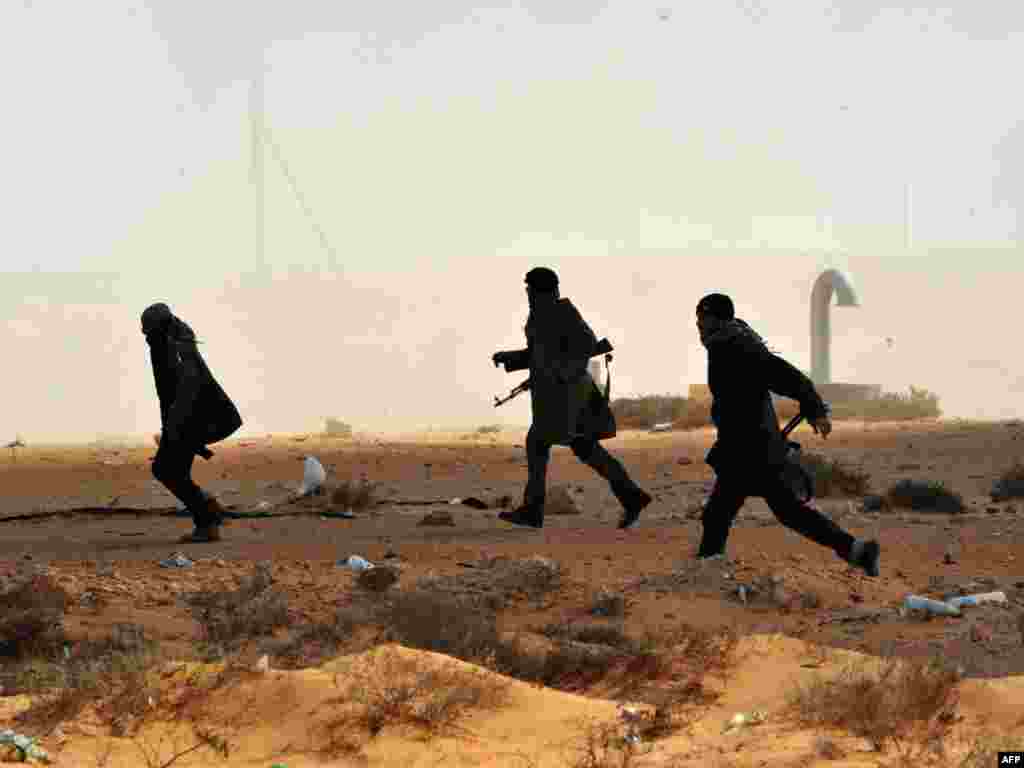 Libyan rebel fighters run to give assistance to their comrades some 10 kilometers east of the key oil port of Ras Lanuf. Photo by Roberto Schmidt for AFP