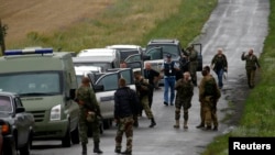 Pro-Russian separatists watch as OSCE monitors arrive at the crash site on July 18