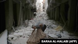 A Syrian resident grasps a mattress amid rubble following a reported overnight air strike by government forces on July 14, 2014 in the al-Firdous neighborhood of the northern city of Aleppo.