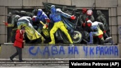 Egy férfi sétál el a szovjet hadsereg emlékműve mellett, amelyet sárga és kék színűre – az ukrán nemzeti színekre – festettek, alatta a „Dicsőség Ukrajnának” felirattal. Szófia, 2022. február 28.