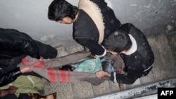 Чоловіки виносятя тіля загиблих в околиці міста Хомс
