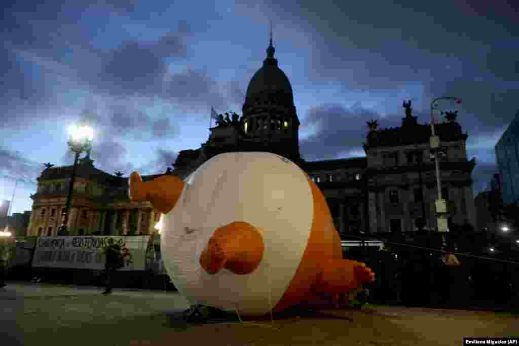 Opponents of the G20 summit deflate a giant doll depicting U.S. President Donald Trump wearing a diaper outside Congress in Buenos Aires. (AP/Emiliana Miguelez)