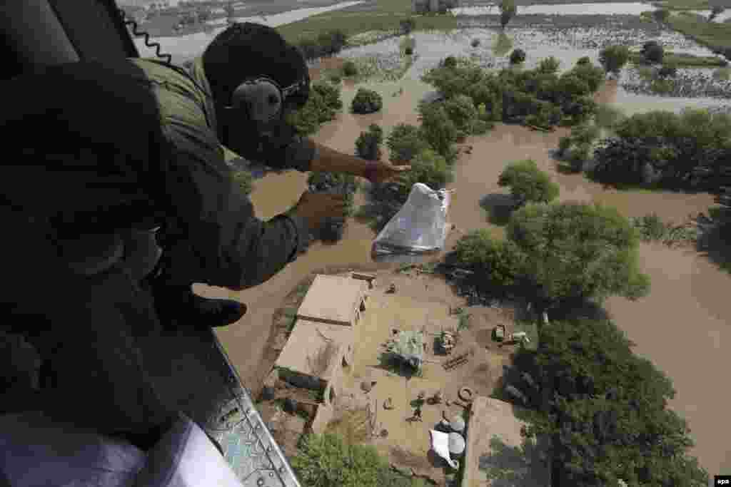 A Pakistani Army soldier distributes food bags from a helicopter in flooded areas in Shujabad, on the outskirts of Multan. Hundreds have died from flooding. (epa/Omer Saleem)