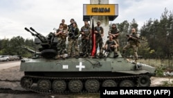 Украинские военные позируют для фото на въезде в город Изюм Харьковской области, который был освобожден от российской армии ранее, 17 сентября 2022 года